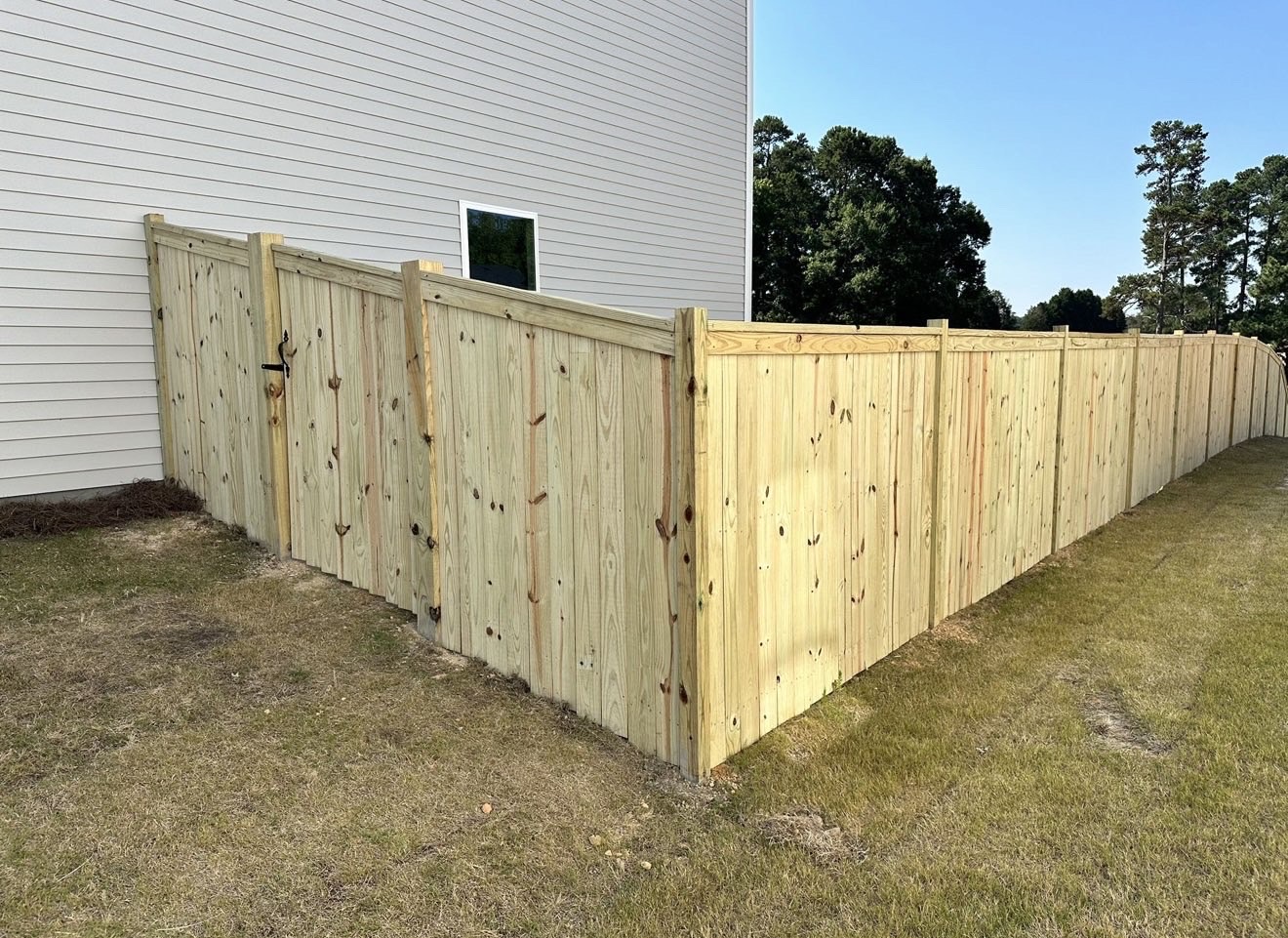 Privacy fence with gate alongside a home
